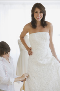 Bride having dress fitted.