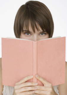 Woman holding open book over face.