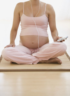 Pregnant woman sitting on yoga mat.