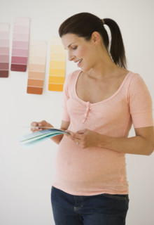 Pregnant woman looking at paint swatches.