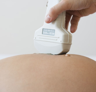 Ultrasound wand on pregnant woman .