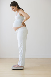 Pregnant woman standing on scale.