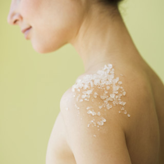 Nude woman with spa salt treatment on shoulder.