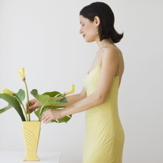 Woman arranging flowers in vase.