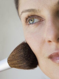 Woman applying make up with brush.