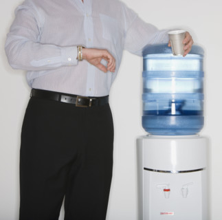 Businessman checking watch next to water cooler.