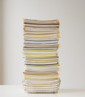Large stack of paperwork in wire basket.