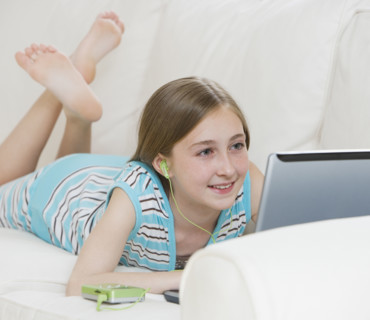 Girl using laptop on sofa.