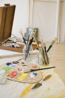 Artist’s palette and paintbrushes on table.