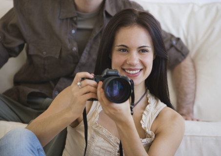 Woman holding camera next to face.