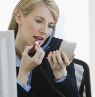 Businesswoman applying lipstick.
