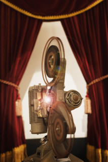Old fashioned movie projector in between stage curtains.