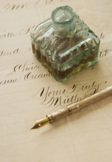 Quill pen and ink bottle on old letter.
