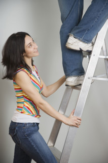 Woman holding ladder while man climbs. Date : 2006