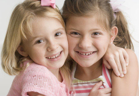 Two young sisters hugging and smiling. Date : 2006