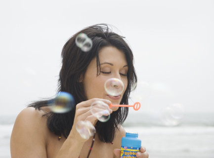 Woman blowing bubbles at beach. Date : 2006