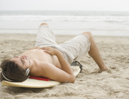 Man laying on surfboard at beach. Date : 2006