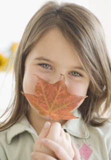Girl holding autumn leaf in front of face. Date : 2006