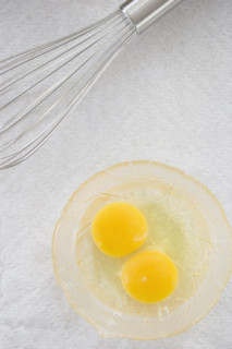 High angle view of whisk next to eggs in bowl. Date : 2006