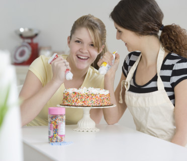 Teenage girls decorating cake. Date : 2007