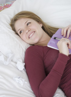 Teenage girl holding journal on bed. Date : 2007
