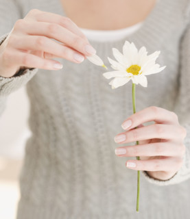 Woman pulling petal off flower. Date : 2007