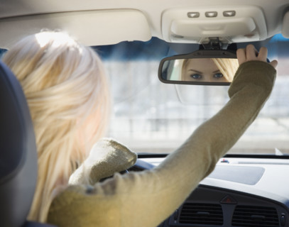 Woman adjusting car rear view mirror. Date : 2007