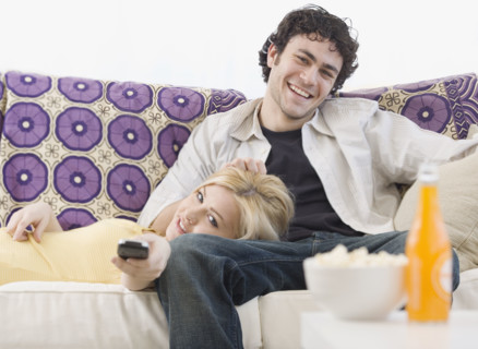 Couple watching television on sofa. Date : 2007