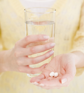 Woman holding water and medication. Date : 2007