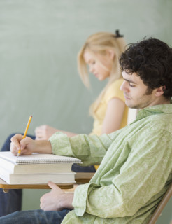 Man writing at desk in classroom. Date : 2007