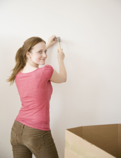 Woman hammering nail in wall. Date : 2006