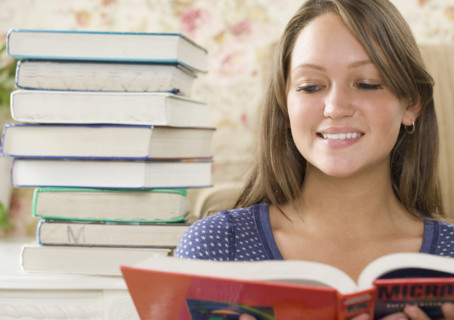 Young woman reading next to stack of books. Date : 2006
