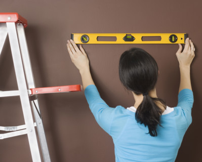 Woman using level on wall. Date : 2006