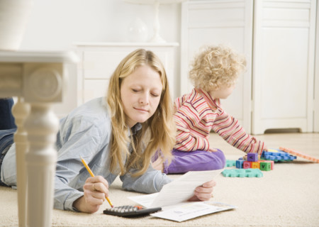 Mother working on calculator while child plays. Date : 2006