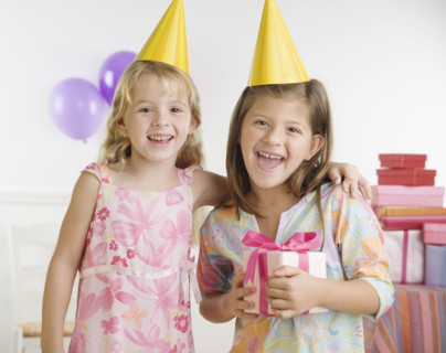 Young sisters wearing party hats and holding gift. Date : 2006