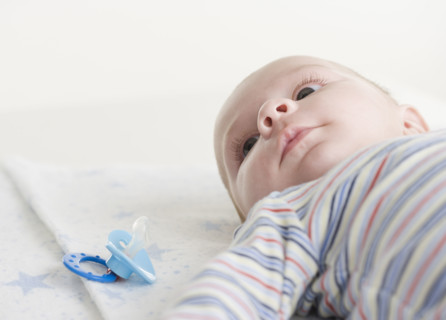 Close up of baby lying down next to pacifier. Date : 2006