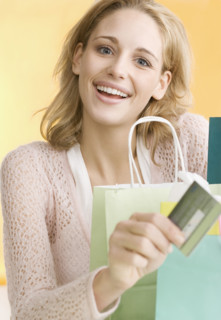 Woman with shopping bags holding credit card   . Date : 2006