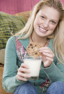 Young woman enjoying a cookie and milk. Date : 2006