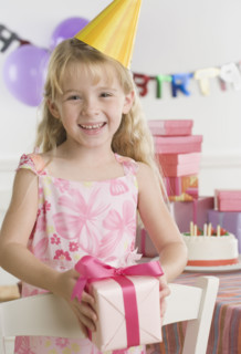 Young girl wearing party hat and holding gift. Date : 2006