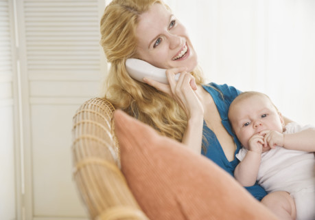 Mother holding baby and talking on the phone. Date : 2006
