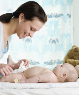 Mother changing baby’s diaper. Date : 2006