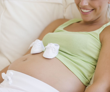 Pregnant woman with baby shoes on belly. Date : 2007