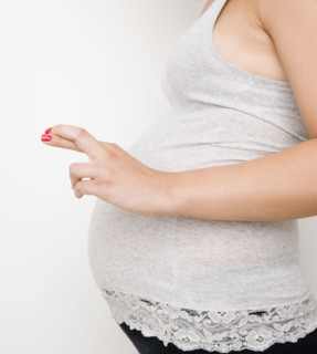 Pregnant woman with fingers crossed. Date : 2007