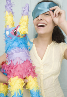 Woman holding pinata and peeking under blindfold. Date : 2007