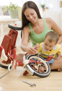 Mother holding baby and fixing tricycle. Date : 2007