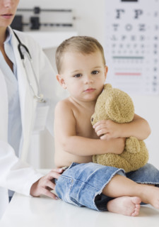 Baby hugging teddy bear at doctor. Date : 2007