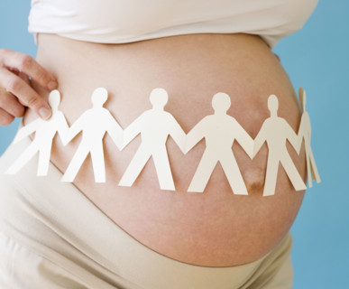 Pregnant woman holding paper dolls around belly. Date : 2007
