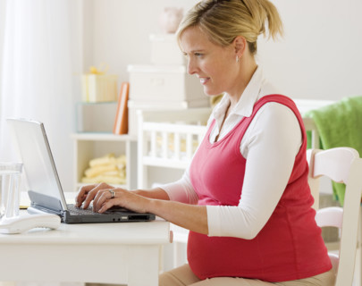 Pregnant woman typing on laptop. Date : 2007