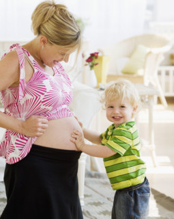 Baby touching mother’s pregnant belly. Date : 2007