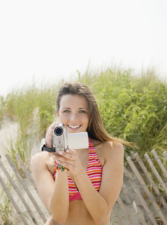 Woman holding video camera at beach. Date : 2007
